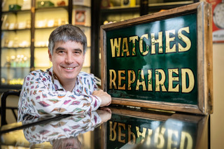 Geoff Allnutt of JE Allnutt & Son next to a 'watches repaired' sign at his shop in West Street, Midhurst, Sussex.