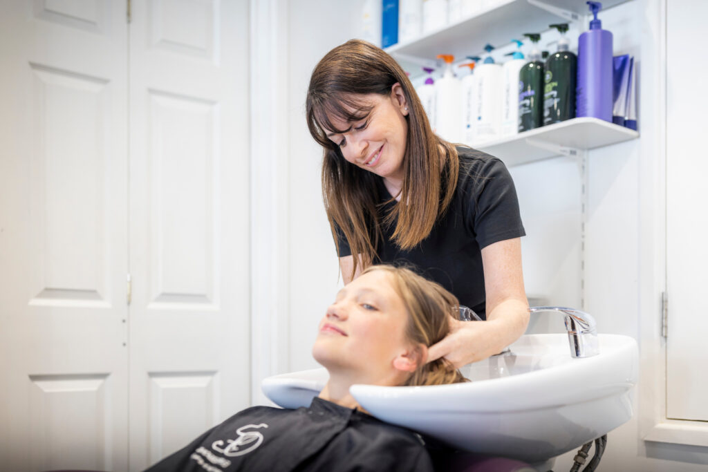 A client getting their hair washed by a staff member at Expressions Hair hairdresser in Midhurst, West Sussex.