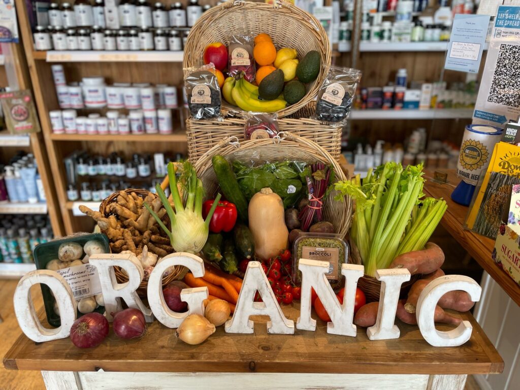 A table of organic fruit and vegetables on a table with wooden letters spelling 'organic' pictured inside Down to Earth organic food sellers in Midwest, Sussex.