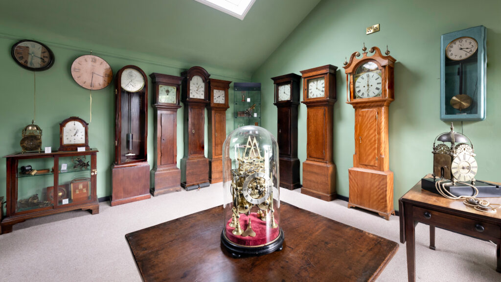 Interior views of JE Allnutt & Son, watch and clock repairs and jewellers showcasing loncase clocks in West Street, Midhurst, Sussex.