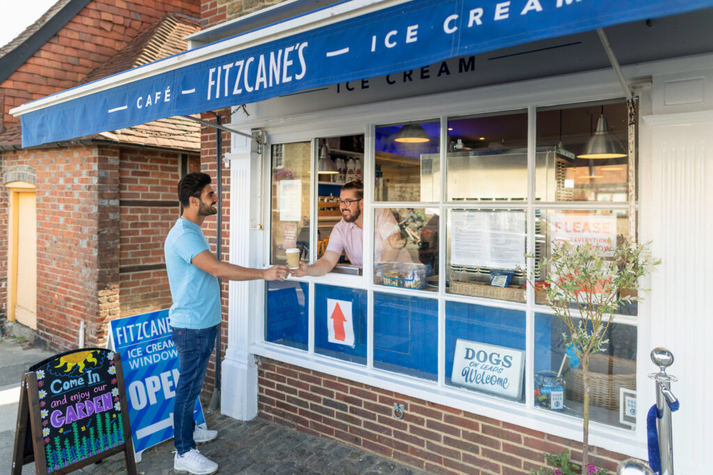 A staff member serving a customer a hot drink through the window at Fitzcane's Ice-Cream Cafe in Midhurst.