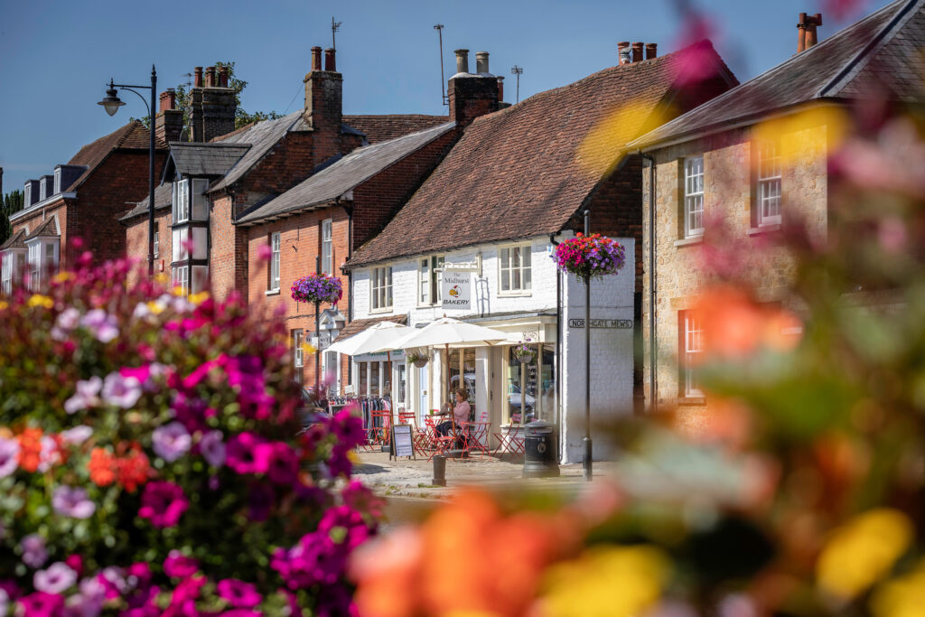 A view of The Midhurst Bakery in North Street, Midhurst, with colourful blurred flowers in the foreground.