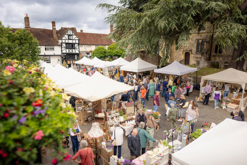 Midhurst town square during Midhurst Vintage Fair with many people and 10 white gazebos.