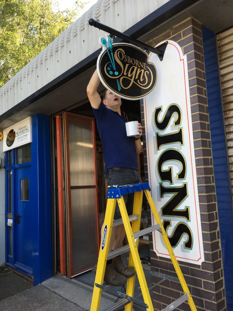 A staff member of Osborne Signs Ltd, painting the sign of Osborne Signs Ltd