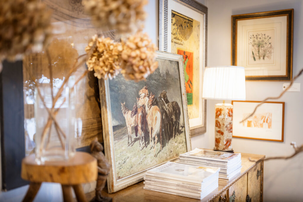 A closeup of four country house style paintings and a lamp inside Olive Interiors in Midhurst, West Sussex.