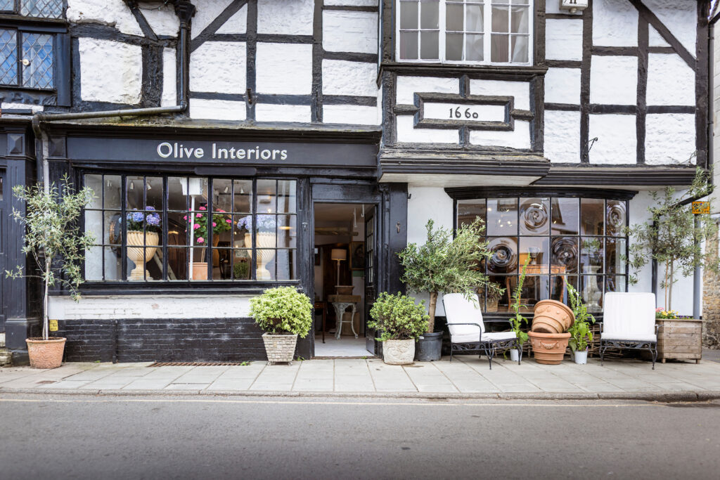 Exterior of Olive Interiors in West Street Midhurst with furniture and plants outside.